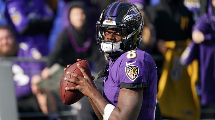 Lamar Jackson looks straight ahead while preparing to throw a football in warmups